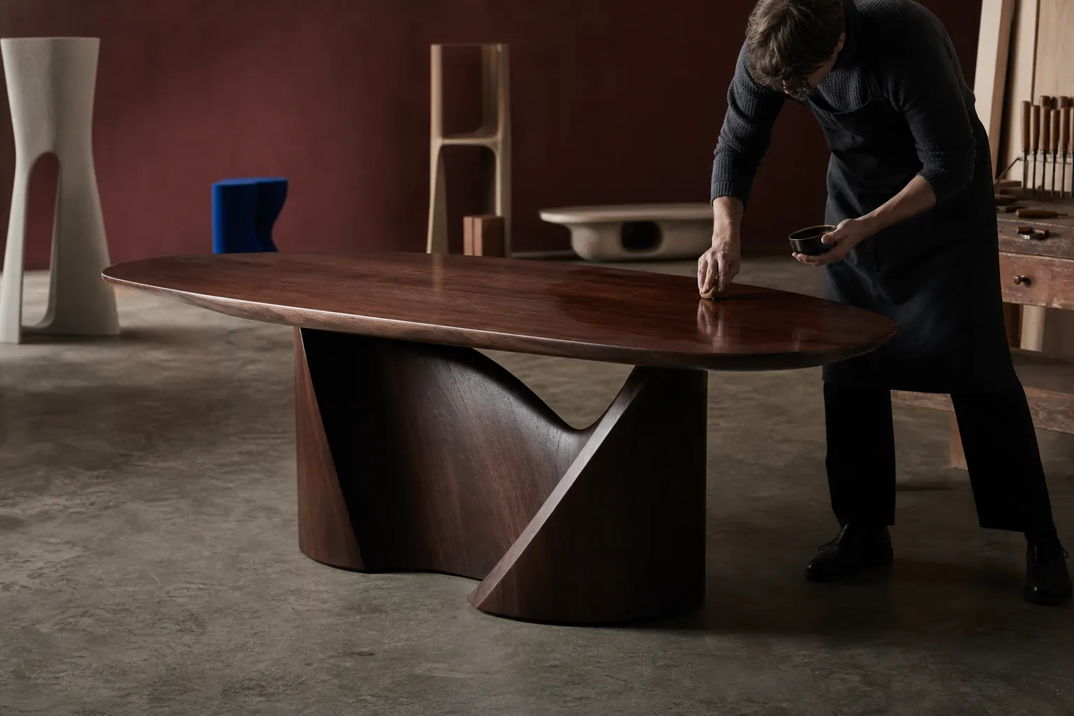 Ébéniste appliquant une finition sur une table contemporaine en noyer